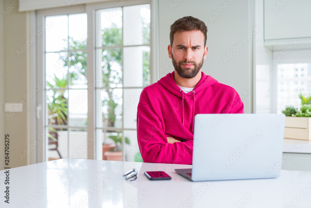Handsome man working using computer laptop skeptic and nervous, disapproving expression on face with crossed arms. Negative person. Handsome man working using computer laptop skeptic and nervous, disapproving expression on face with crossed arms. Negative person.