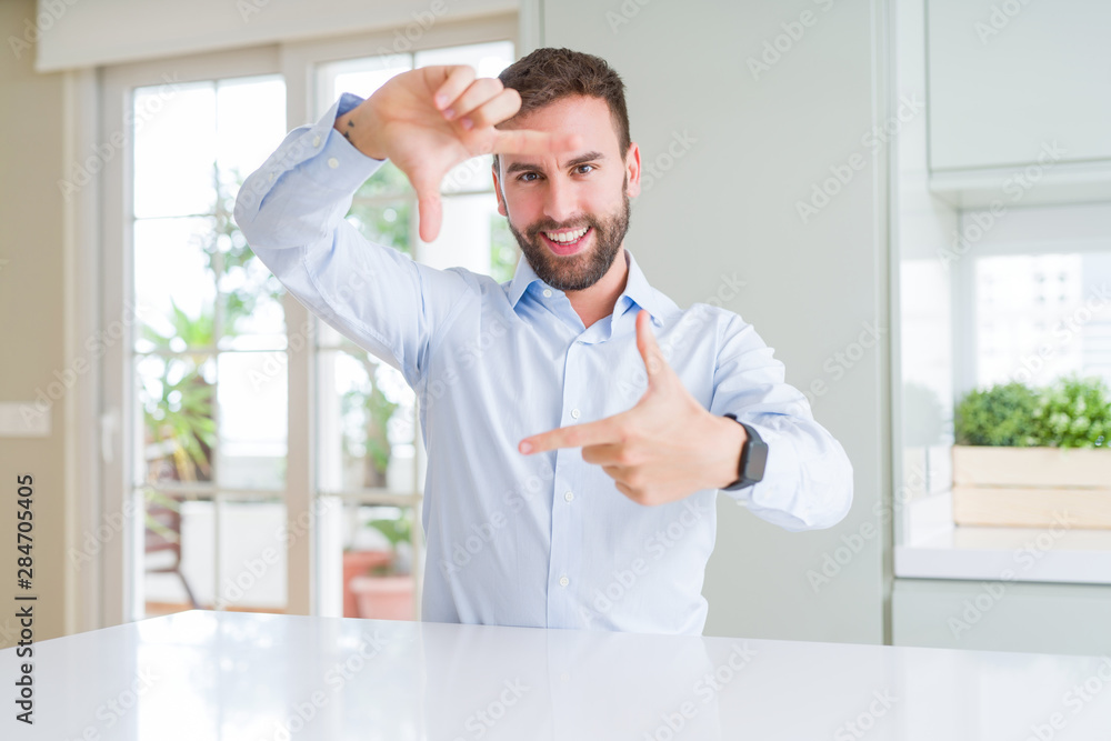 Fototapeta premium Handsome business man smiling making frame with hands and fingers with happy face. Creativity and photography concept.
