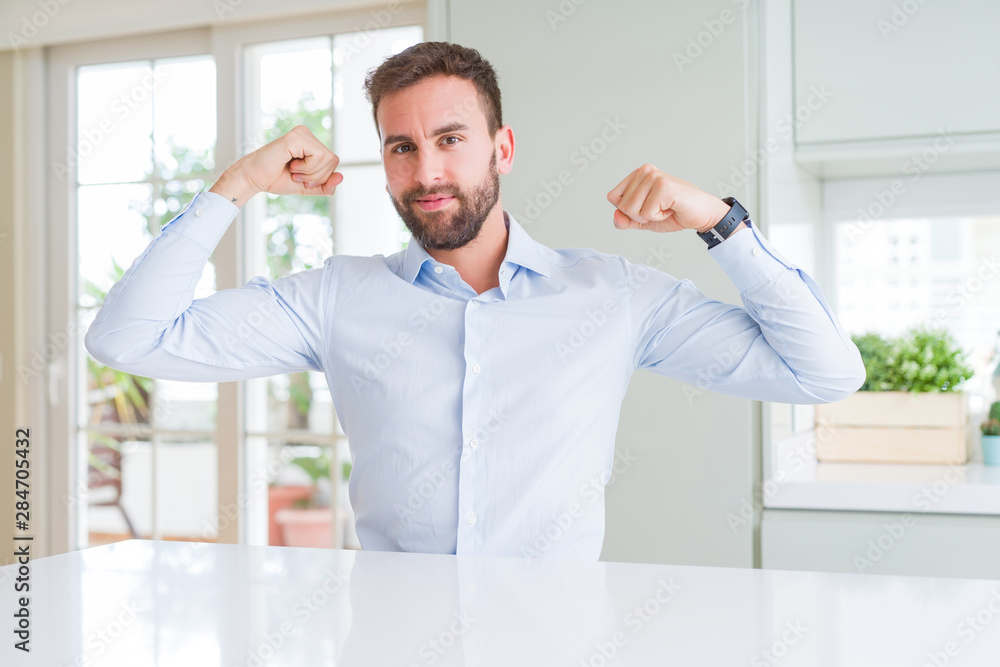 Fototapeta premium Handsome business man showing arms muscles smiling proud. Fitness concept.