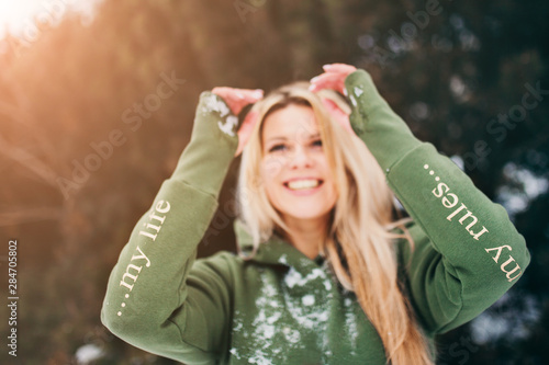 Foto Blue-eyed blonde in a green hoody in the winter in the forest - focus on the sle