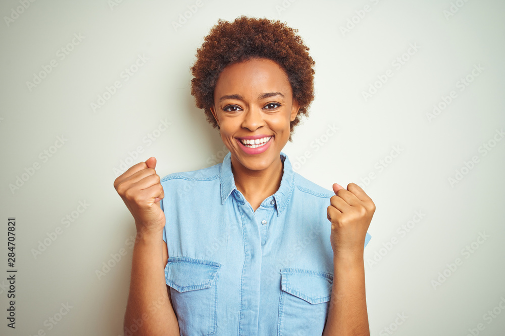 Young beautiful african american woman with afro hair over isolated background celebrating surprised and amazed for success with arms raised and open eyes. Winner concept. Young beautiful african american woman with afro hair over isolated background celebrating surprised and amazed for success with arms raised and open eyes. Winner concept.