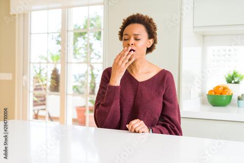 Young beautiful african american woman at home bored yawning tired covering mouth with hand. Restless and sleepiness.