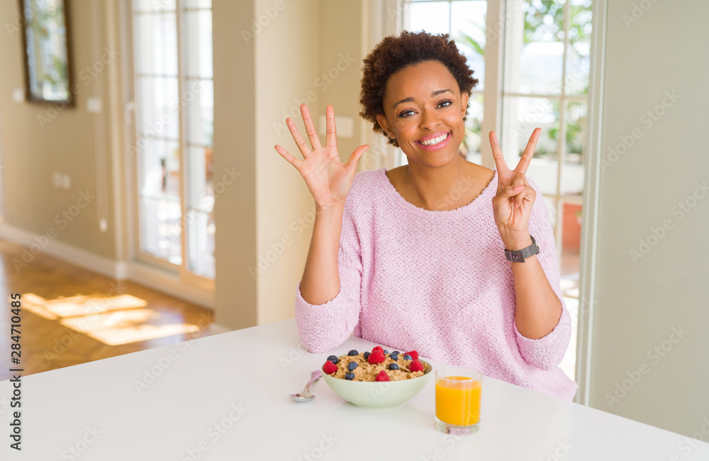 Young african american woman having healthy breakfast in the morning at home showing and pointing up with fingers number seven while smiling confident and happy. Young african american woman having healthy breakfast in the morning at home showing and pointing up with fingers number seven while smiling confident and happy.