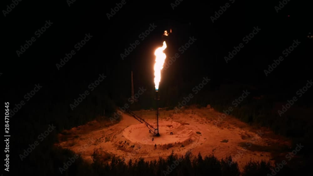 A huge torch of fire on in the middle of the forest at night. gas processing, environmental pollution concept, global warming