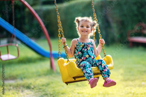 Happy little girl on a swing in the park photo