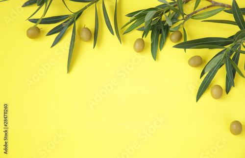 Flat lay. Olive leaves with green olives on a yellow background. Healthy food Mediterranean diet. Pattern, background, texture. With copy space Top view. Abstract background . © Irina Tarzian