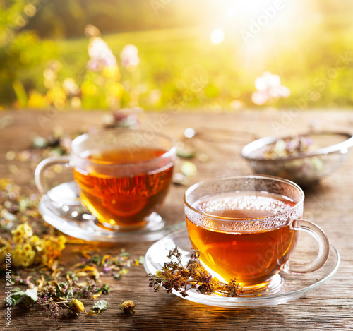 Cups of herbal tea with various herbs at sunset