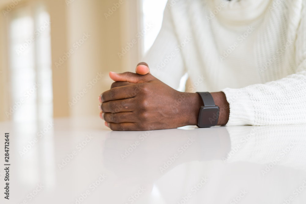 Close up of crossed hands of african man over table