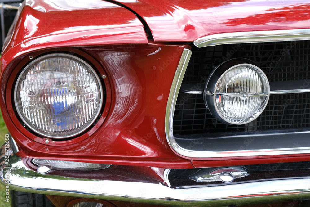 Headlights , radiator and hood of retro red car ckose-up.