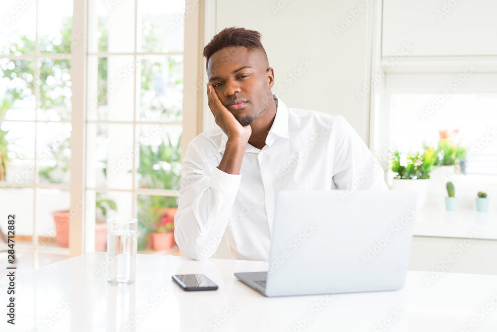 African american business man working using laptop thinking looking tired and bored with depression problems with crossed arms. African american business man working using laptop thinking looking tired and bored with depression problems with crossed arms.