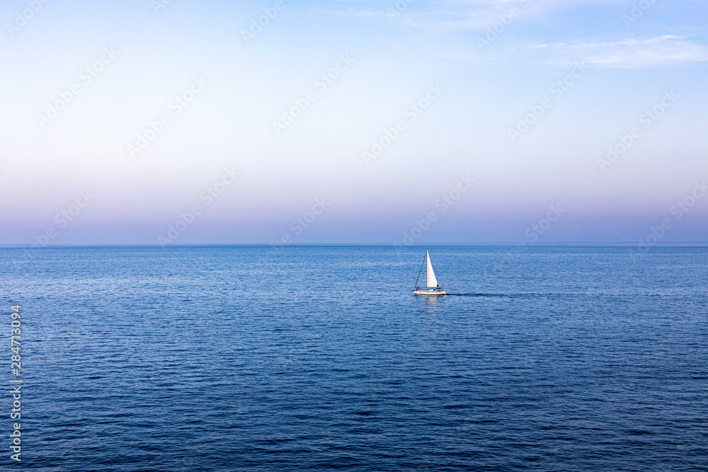 Lonely sailboat sailing at sunset on the Mediterranean