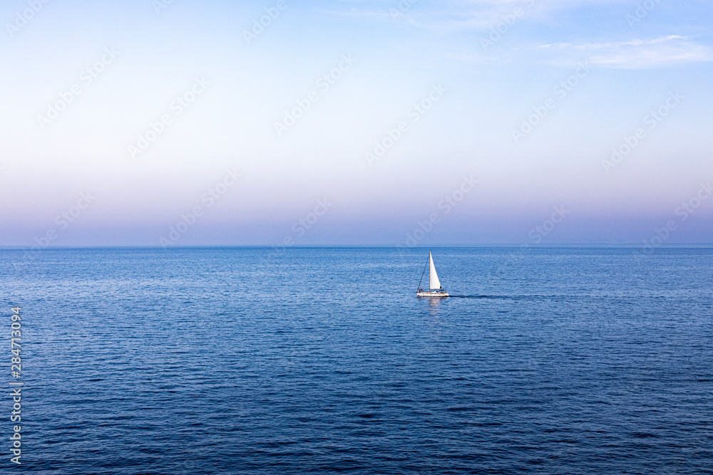 Lonely sailboat sailing at sunset on the Mediterranean Lonely sailboat sailing at sunset on the Mediterranean