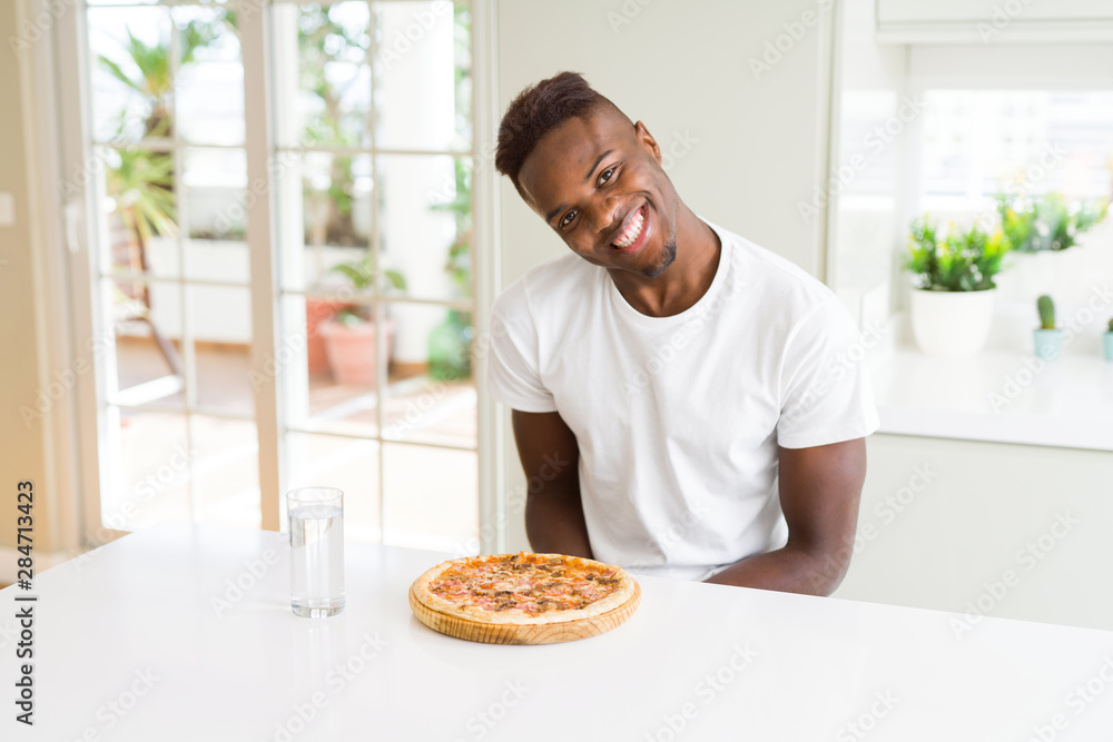 Handsome young african man holding and showing smiling proud homemade cheese pizza Handsome young african man holding and showing smiling proud homemade cheese pizza