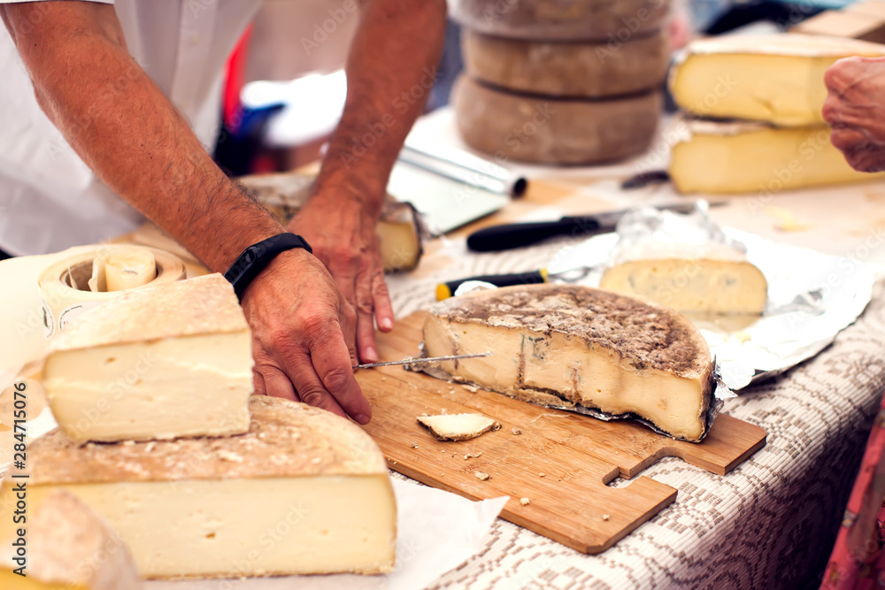 Seller prepares cheese for the custumers at cheese festival. Organic and farm food Seller prepares cheese for the custumers at cheese festival. Organic and farm food