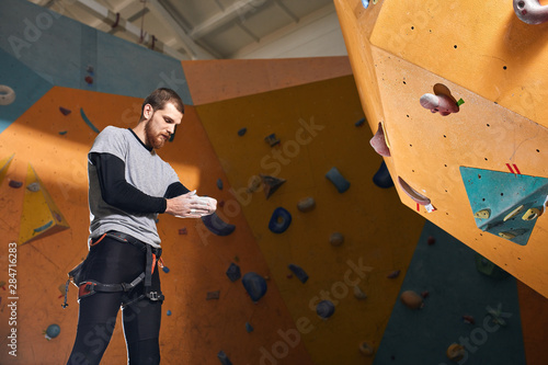 Tableau sur toile Handsome young boulderer without forearm, applies chalk to keep hands dry and provide firmer grip during training, looks concentrated and focused, plans to climb the hardest wall