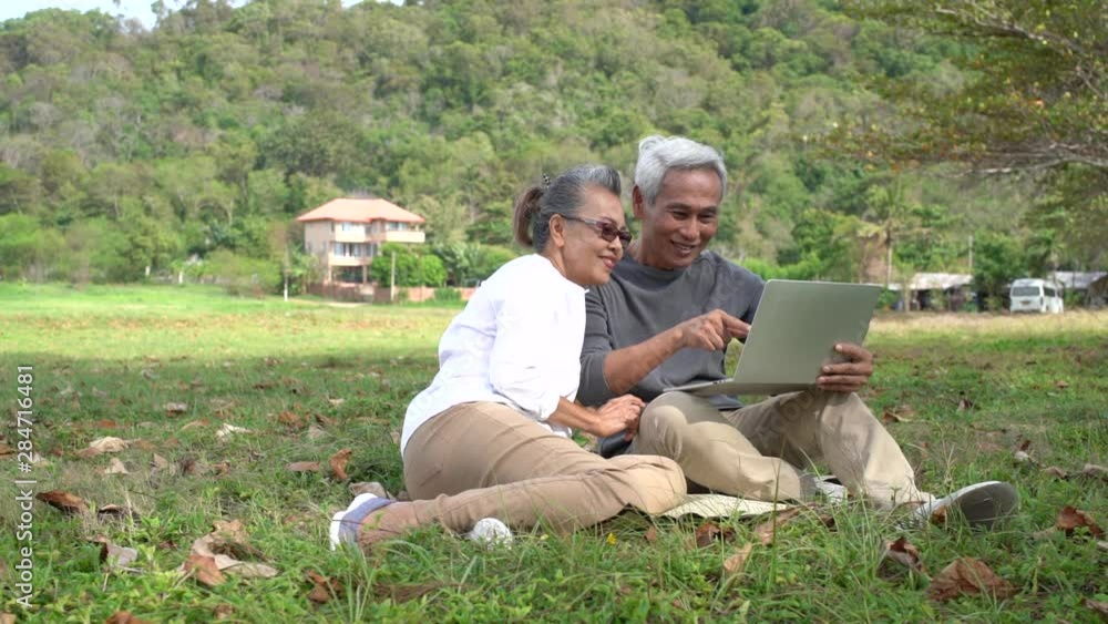 Asian couple senior elder retire relax and watching laptop computer technology at front house family together happiness people lifestyle, Slow motion footage Asian couple senior elder retire relax and watching laptop computer technology at front house family together happiness people lifestyle, Slow motion footage