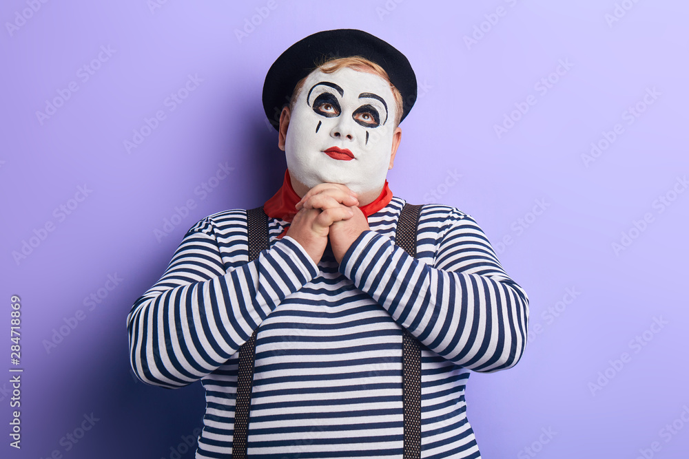 portrait of fat mime man pretending praying on blue background. copy space. joy, fun, comedy. portrait of fat mime man pretending praying on blue background. copy space. joy, fun, comedy.