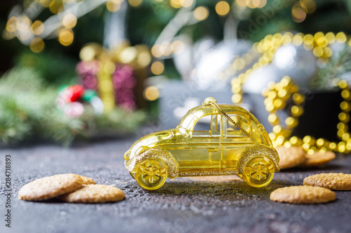 Yellow retro toy car delivering Christmas or New Year gifts on dark background