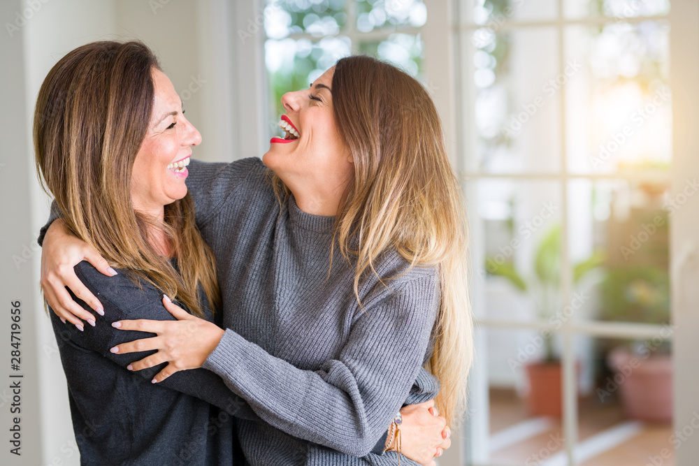 Beautiful family of mother and daughter together, hugging and kissing at home - obrazy, fototapety, plakaty 