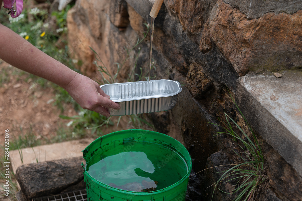 mountain landscape with water tap and green bucket