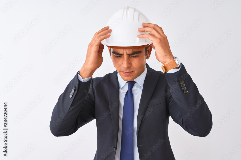 Young handsome architect man wearing suit and helmet over isolated white background suffering from headache desperate and stressed because pain and migraine. Hands on head. Young handsome architect man wearing suit and helmet over isolated white background suffering from headache desperate and stressed because pain and migraine. Hands on head.