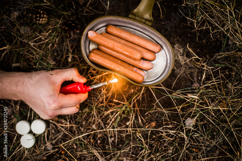 Sausages are fried over an open fire in a pan