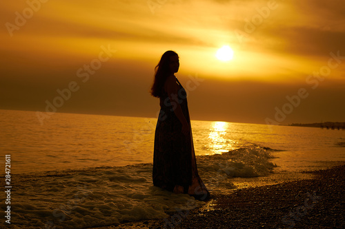 Silhouette of a girl in golden sunset by the sea