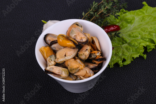 Pickled mussels in the bowl served pepper, garlic and salad