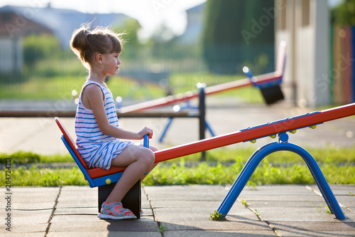 Valokuva Cute young child girl outdoors on see-saw swing on sunny summer day