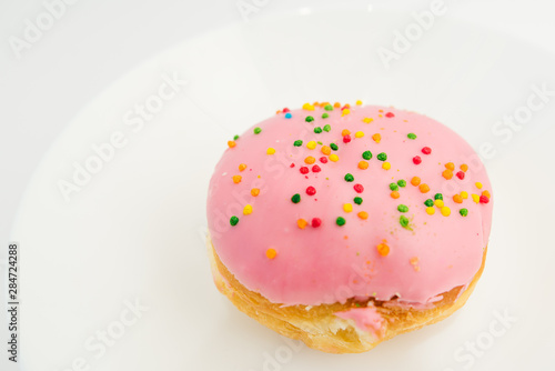 Pink round donut on white plate on white background