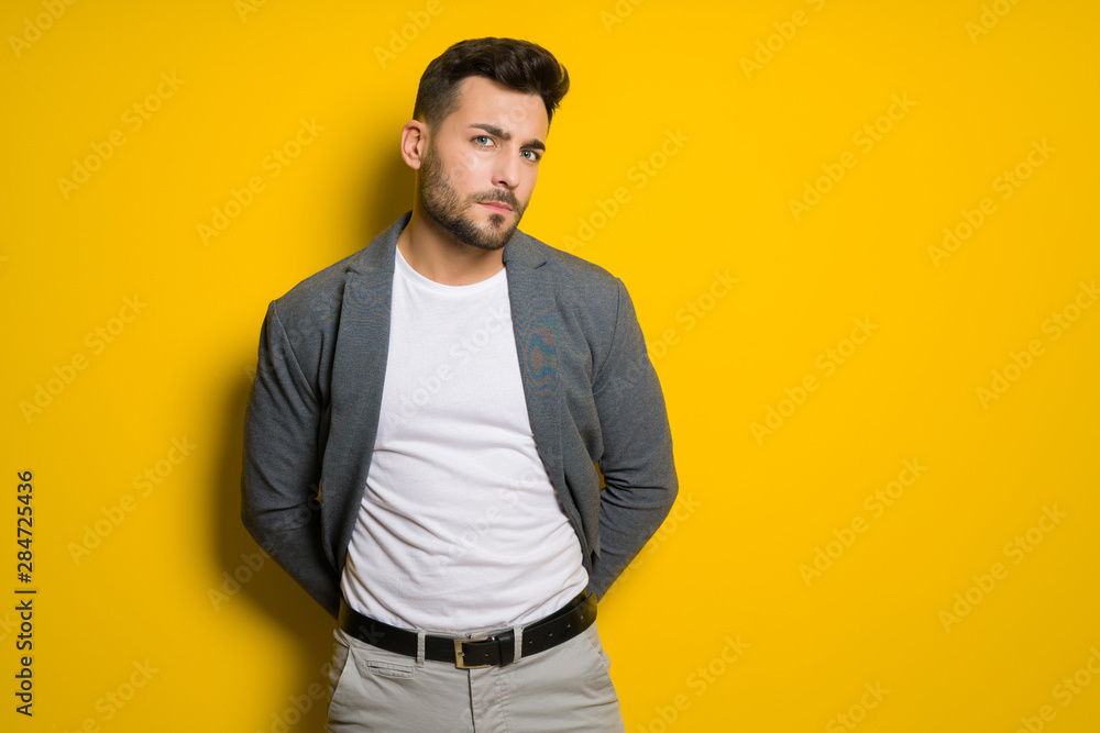 Young handsome man possing and modeling over yellow isolated background Young handsome man possing and modeling over yellow isolated background