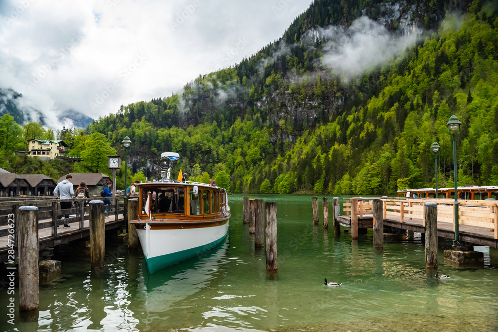 Scenic view on Konigssee Lake with wooden pier with moored touristic ship
