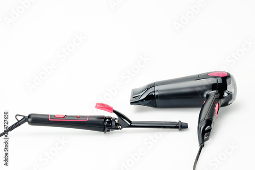 Hair iron and dryer on white mat background with copy space