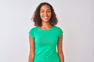 Young brazilian woman wearing green t-shirt standing over isolated white background with a happy and cool smile on face. Lucky person.