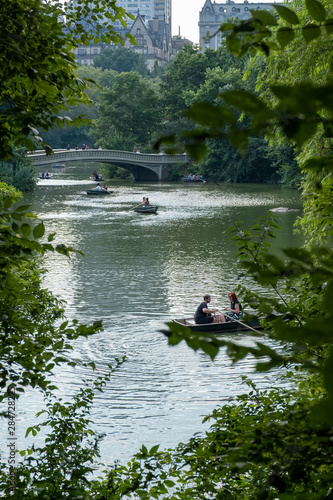 Rowing a boat at Central Park lake, in the middle of trees and buildings as background.