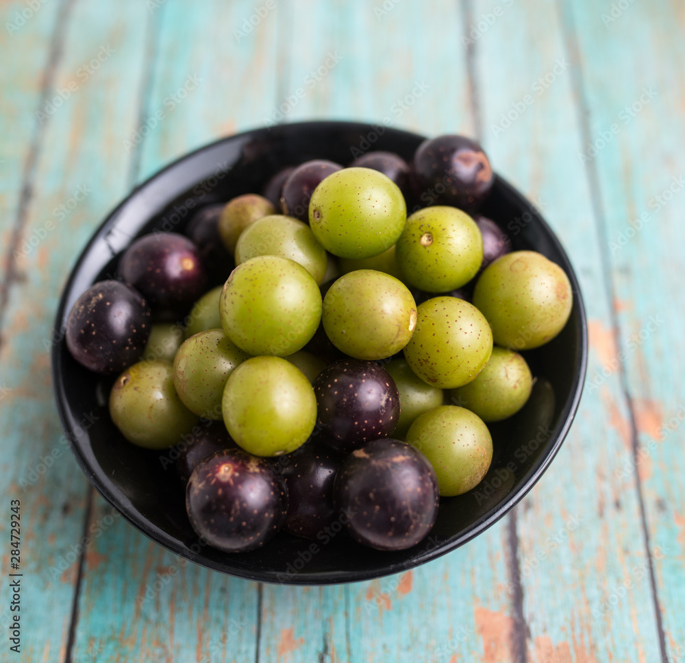 Muscadine grapes are also known as swamp grapes, Florida grapes in a bowl on wood background Muscadine grapes are also known as swamp grapes, Florida grapes in a bowl on wood background