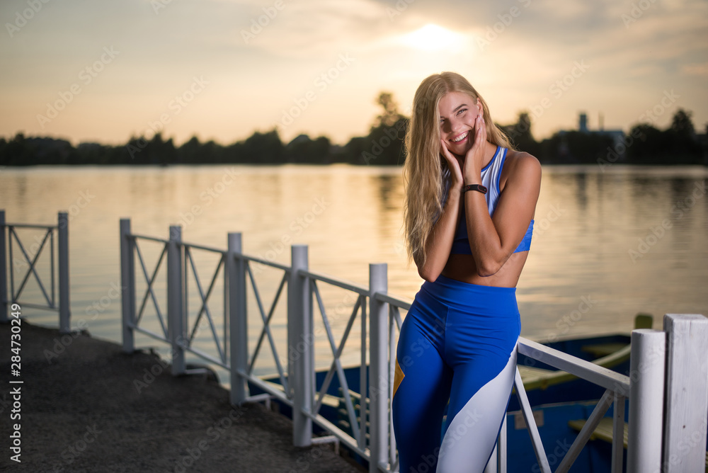 Beautiful sports girl posing on sunset background. Great body.