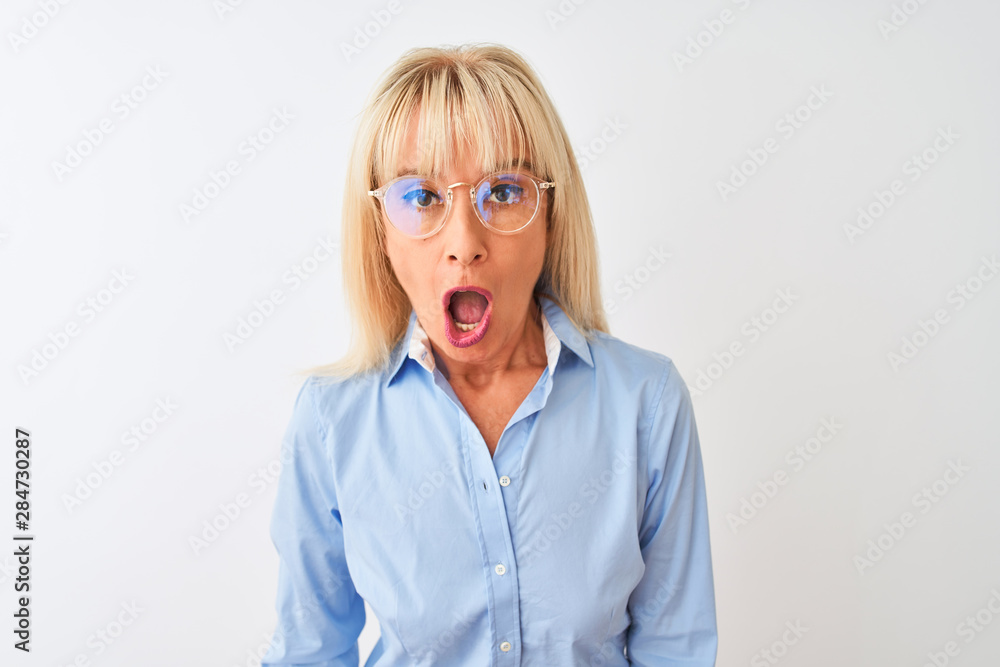 Middle age businesswoman wearing glasses and shirt standing over isolated white background scared in shock with a surprise face, afraid and excited with fear expression