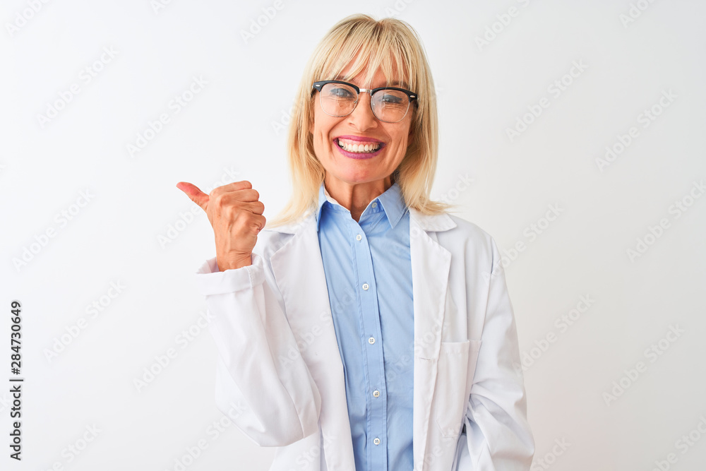Middle age scientist woman wearing glasses standing over isolated white background smiling with happy face looking and pointing to the side with thumb up. Middle age scientist woman wearing glasses standing over isolated white background smiling with happy face looking and pointing to the side with thumb up.