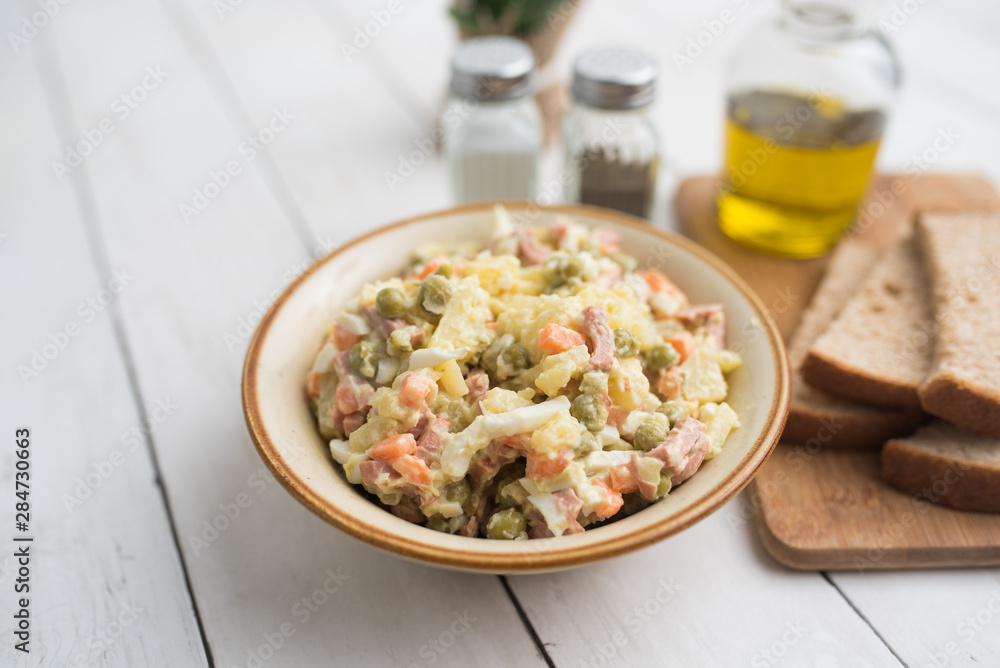 Bowl of traditional Russian salad called Olivie, Russian New Year or Christmas salad on wooden background. Salad from cooked vegetables. Potato salad. Bowl of traditional Russian salad called Olivie, Russian New Year or Christmas salad on wooden background. Salad from cooked vegetables. Potato salad.