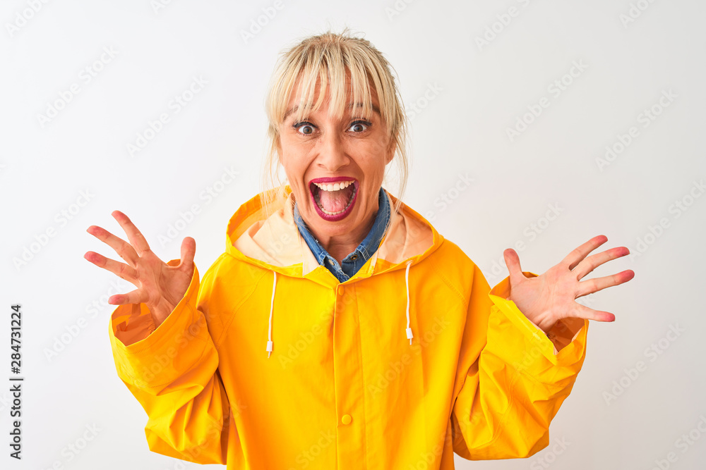 Middle age woman wearing yellow rain coat standing over isolated white background celebrating crazy and amazed for success with arms raised and open eyes screaming excited. Winner concept Middle age woman wearing yellow rain coat standing over isolated white background celebrating crazy and amazed for success with arms raised and open eyes screaming excited. Winner concept