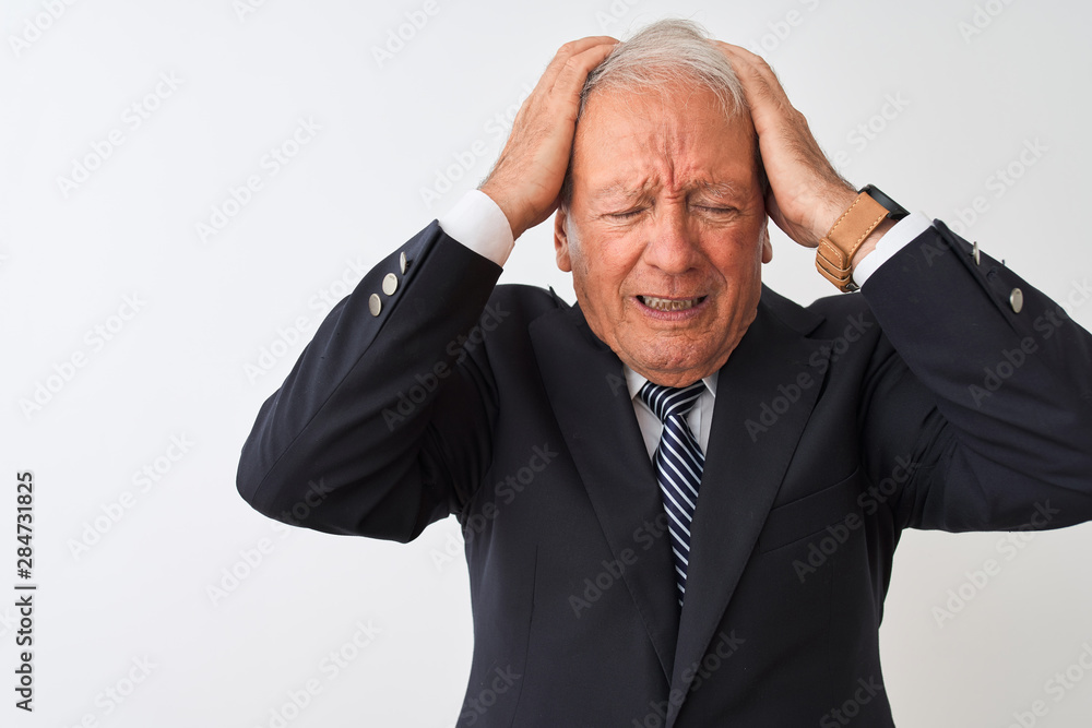 Senior grey-haired businessman wearing suit standing over isolated white background suffering from headache desperate and stressed because pain and migraine. Hands on head. Senior grey-haired businessman wearing suit standing over isolated white background suffering from headache desperate and stressed because pain and migraine. Hands on head.