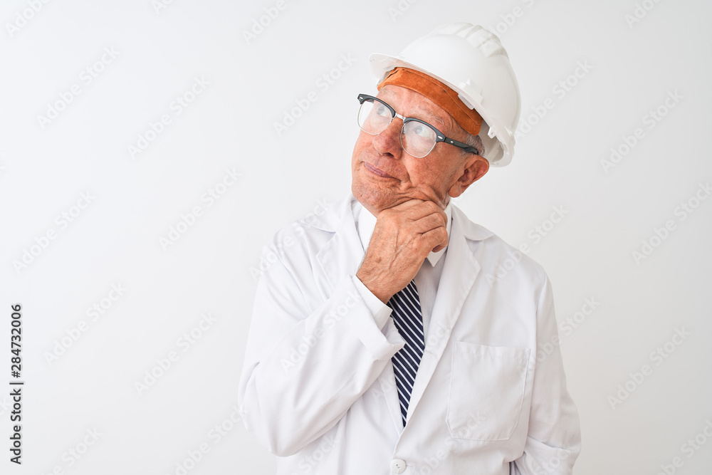 Senior grey-haired engineer man wearing coat and helmet over isolated white background with hand on chin thinking about question, pensive expression. Smiling with thoughtful face. Doubt concept. Senior grey-haired engineer man wearing coat and helmet over isolated white background with hand on chin thinking about question, pensive expression. Smiling with thoughtful face. Doubt concept.