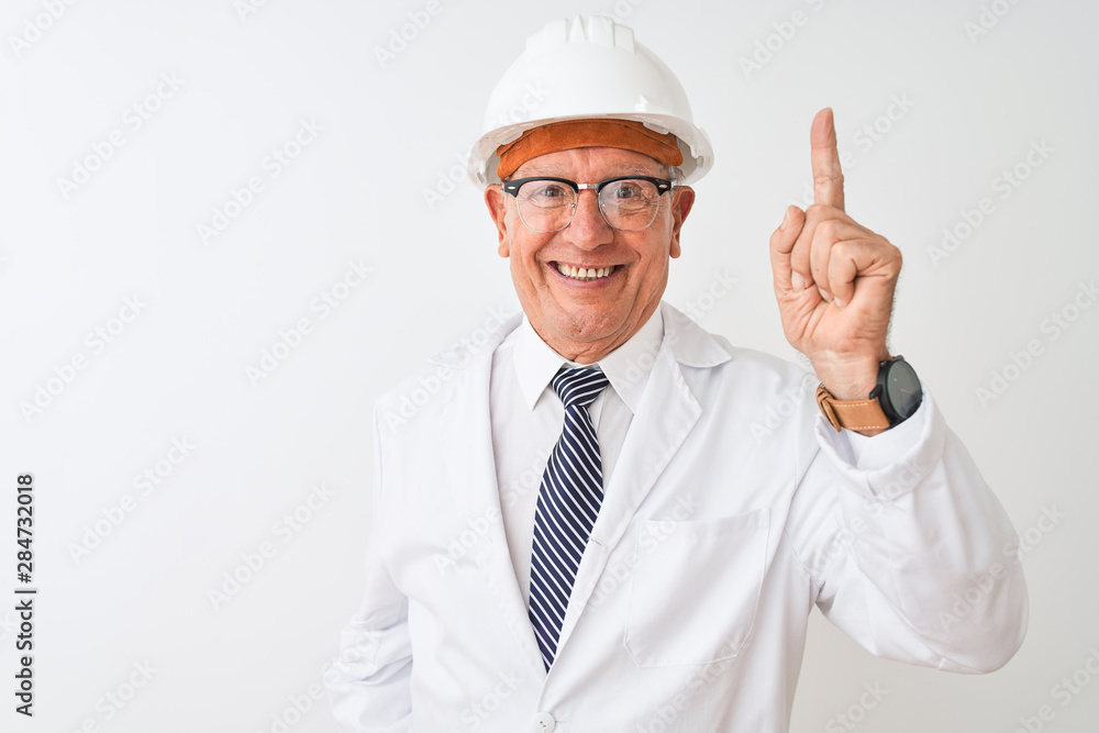 Senior grey-haired engineer man wearing coat and helmet over isolated white background pointing finger up with successful idea. Exited and happy. Number one. Senior grey-haired engineer man wearing coat and helmet over isolated white background pointing finger up with successful idea. Exited and happy. Number one.