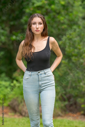 Attractive young 19 year old female in a tank top and denim jeans
