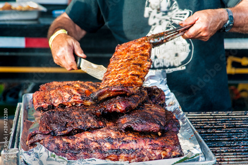 Man prepares several racks of ribs on a barbecue 