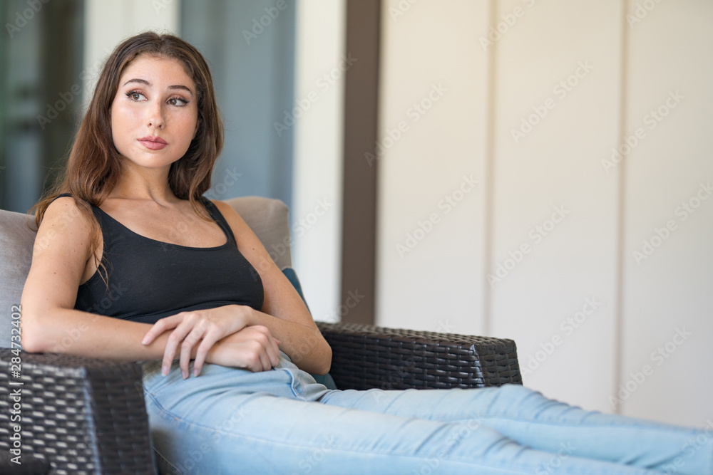 Woman sitting on wicker furniture in the backyard of a house Woman sitting on wicker furniture in the backyard of a house