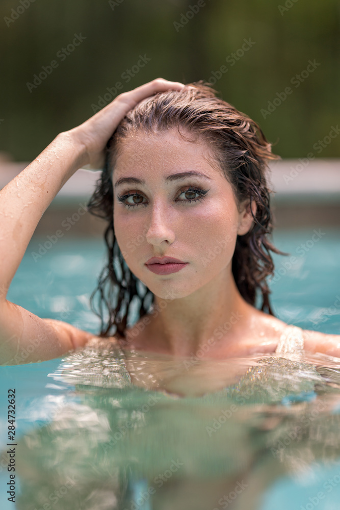 Bikini model posing in a pool with hand on head