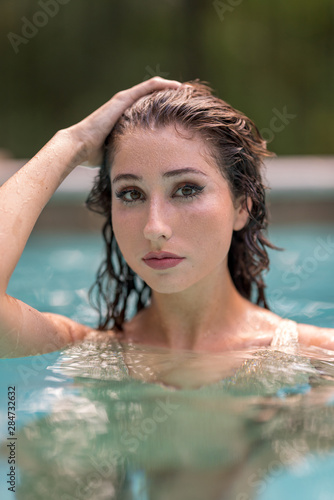 Bikini model posing in a pool with hand on head