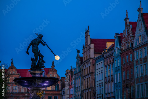 Evening view of Neptune's Fountain with bronze statue in old town in Gdansk Poland. Moon on the trident, hunt moon